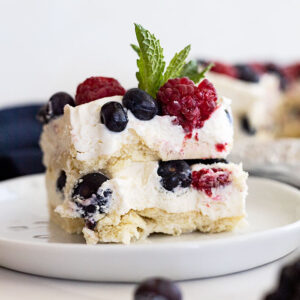 Piece of berry icebox cake on a white plate with a mint garnish.