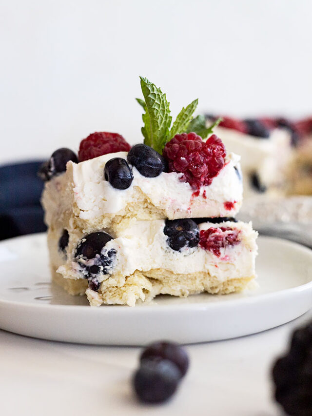 Piece of berry icebox cake on a white plate with a mint garnish.