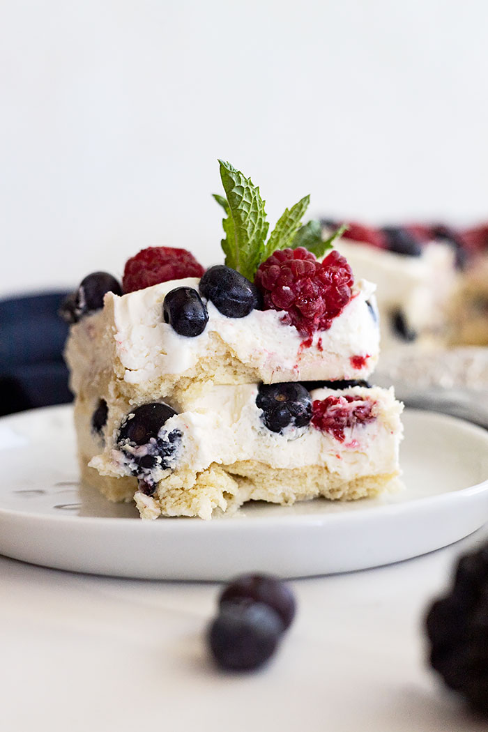 Piece of berry icebox cake on a white plate with a mint garnish.