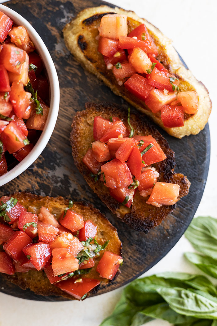 Overhead view of bruschetta on toasted bread on a serving board. 