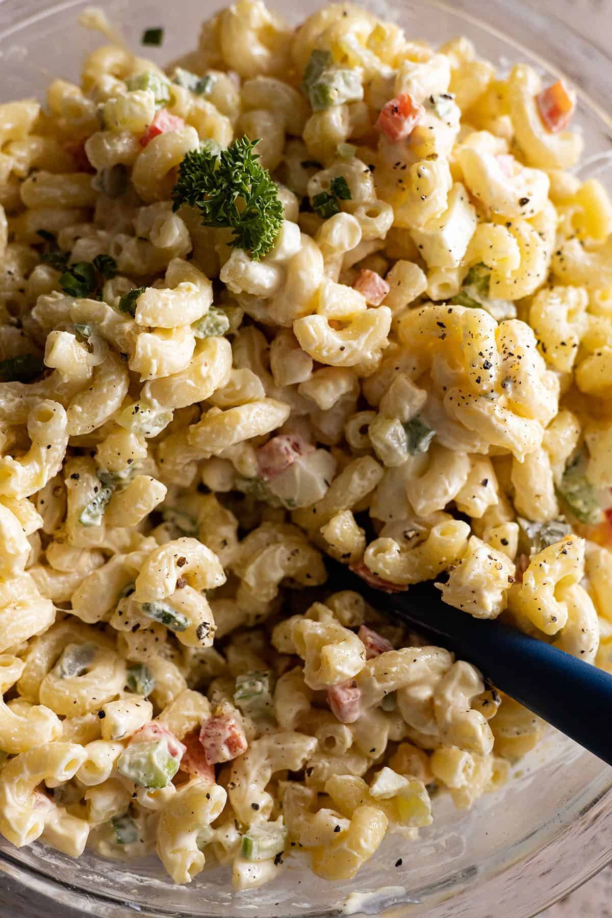 Close of up macaroni salad garnished with parsley and black pepper.