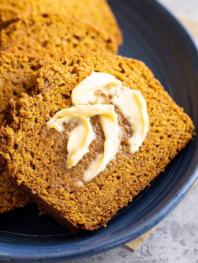 A slice of pumpkin bread with butter melting on it.