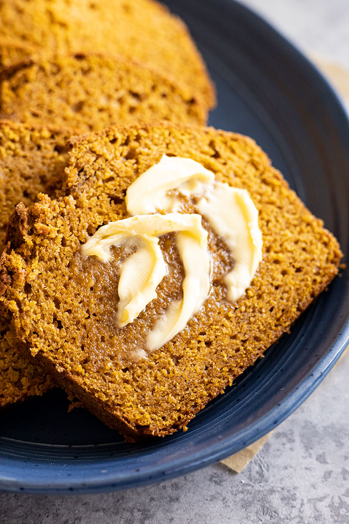 A slice of pumpkin bread with butter melting on it. 