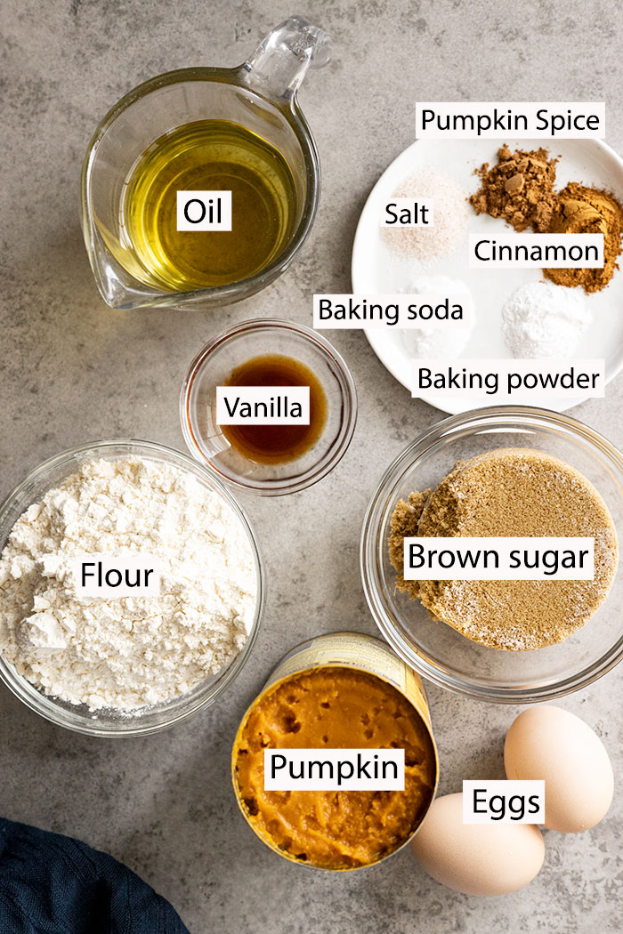 Ingredients to make easy pumpkin bread: flour, pumpkin puree, eggs, oil, brown sugar, vanilla, baking soda, baking powder, cinnamon, pumpkin spice.