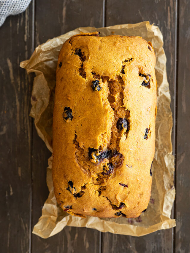 Overhead view of a loaf of pumpkin blueberry bread fresh from the oven.
