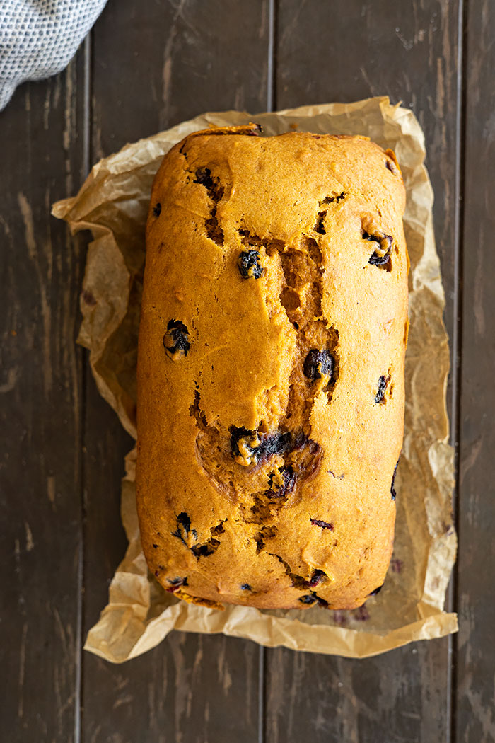 Overhead view of a loaf of pumpkin blueberry bread fresh from the oven. 