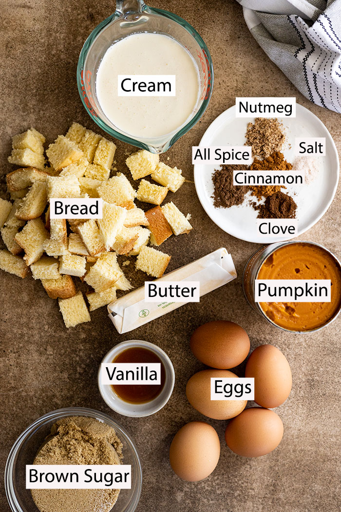 Ingredients to make pumpkin bread pudding: cream, bread, butter, brown sugar, vanilla, eggs, pumpkin, and fall spices.