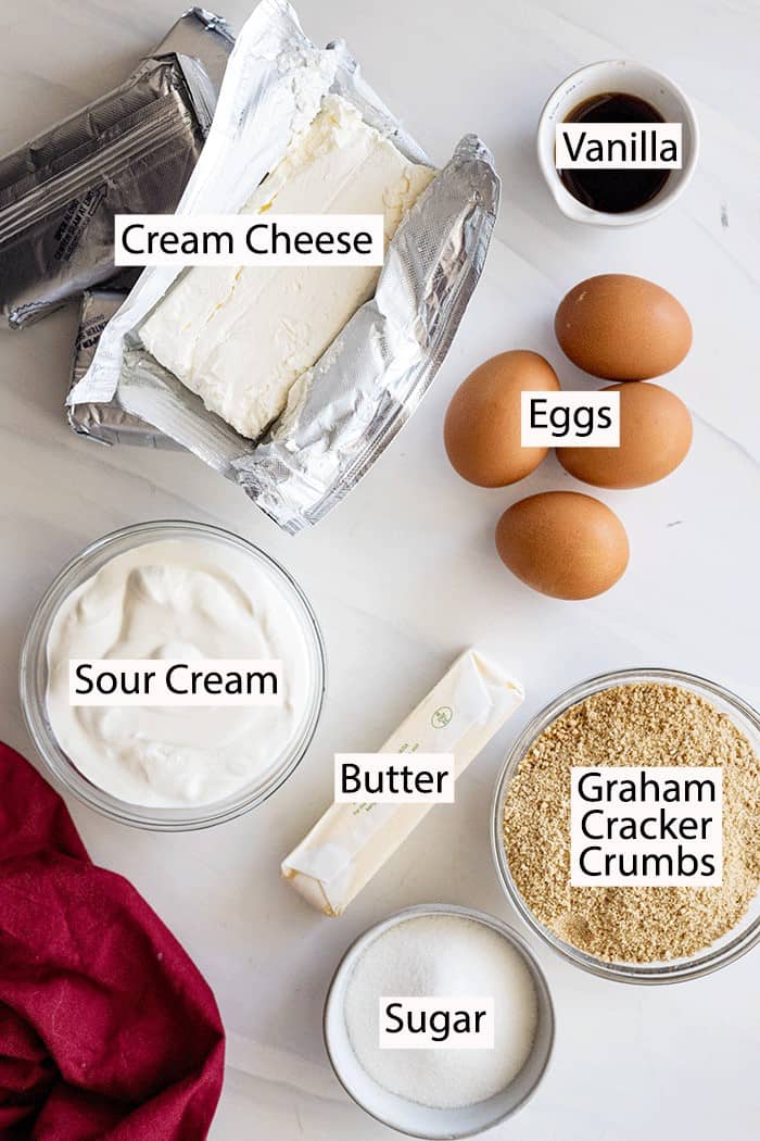 Ingredients for vanilla cheesecake: cream cheese, vanilla, eggs, sour cream, butter, sugar, graham cracker crumbs. 