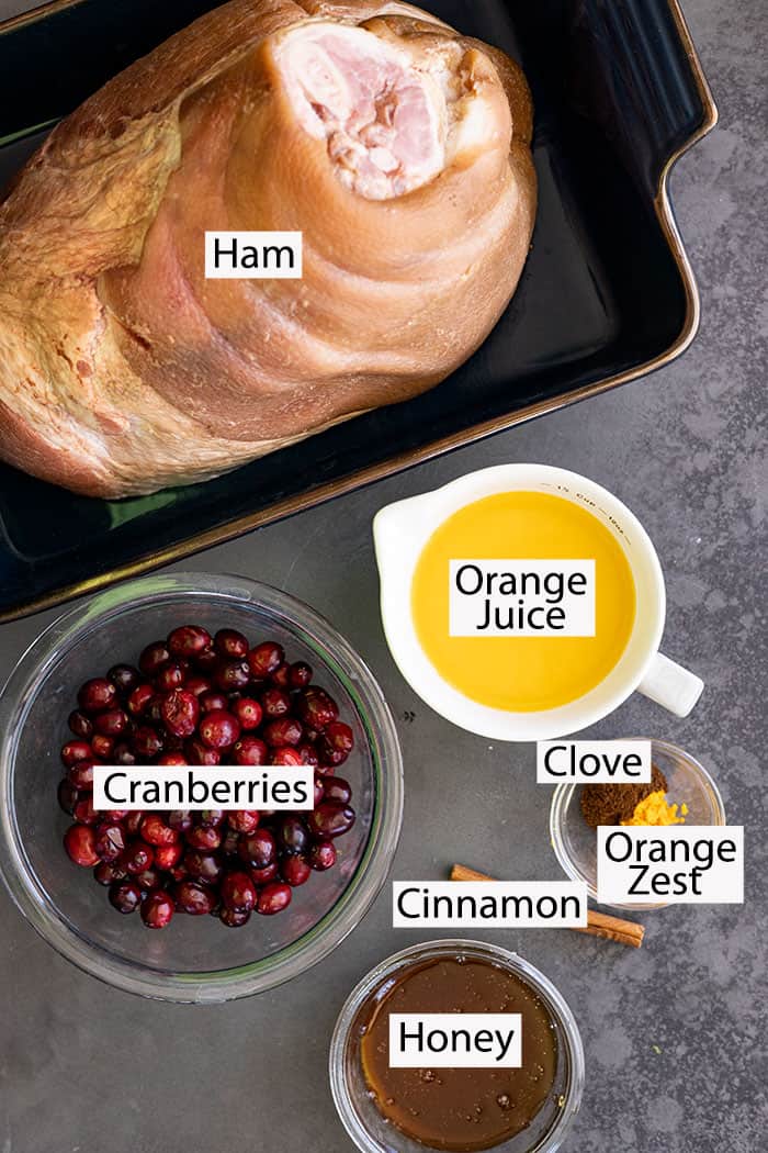 Ingredients to make ham: cranberries, orange juice, honey, orange zest, clove, cinnamon, ham.