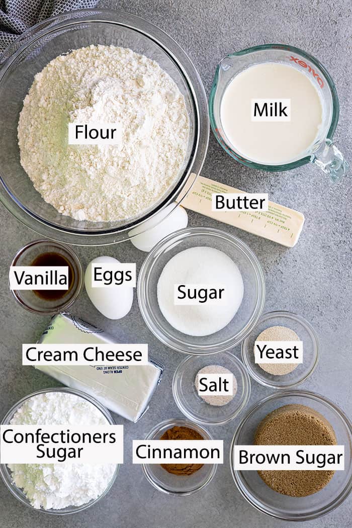 Ingredients to make cinnamon rolls: flour, milk, butter, eggs, sugar, yeast, salt, cinnamon, brown sugar, plus frosting.
