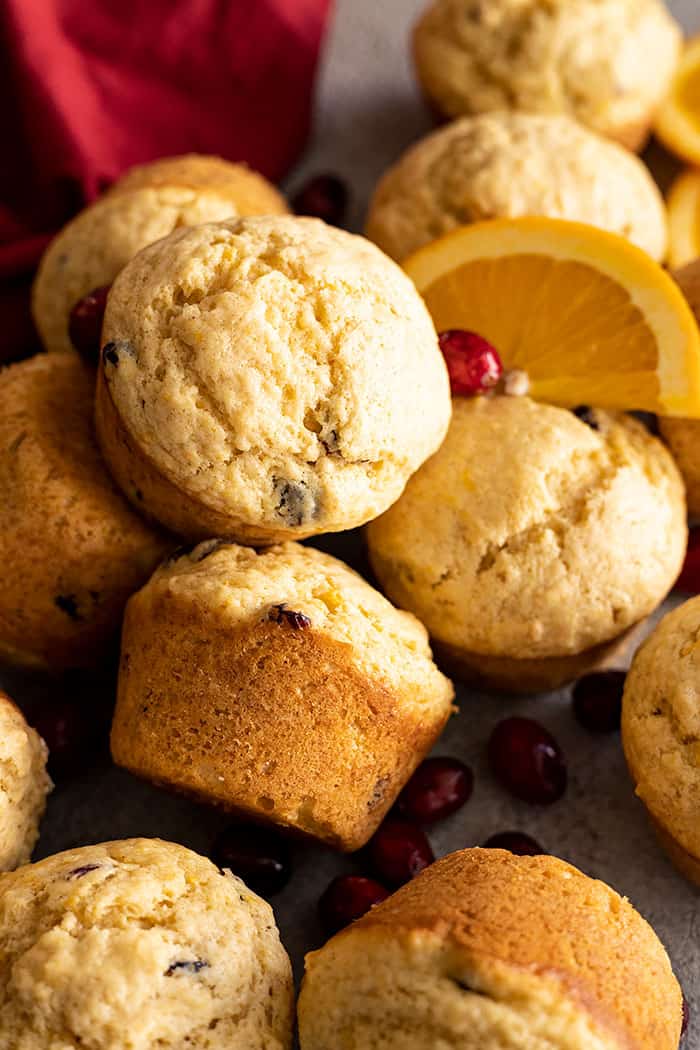 Overhead view of muffins scattered and piled together. Cranberries and orange slices scattered. 