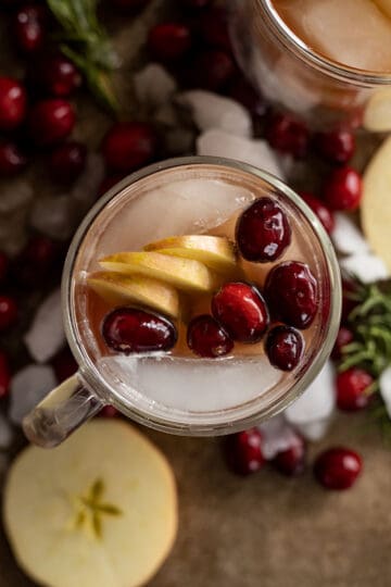 Overhead view of apple cranberry moscow mule in a mug decorated with apple slices and fresh cranberries.