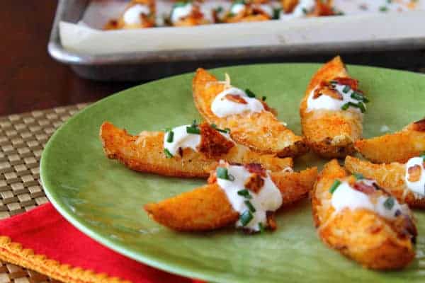 Crispy Potato Wedges on a green plate with sour cream and toppings.