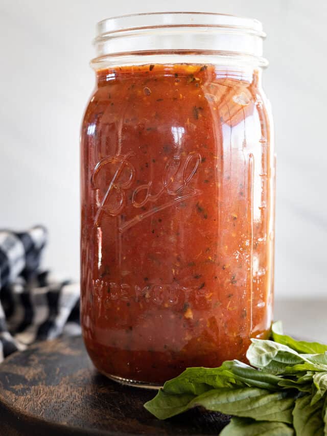 Marinara Sauce in a mason jar with a bunch of basil off to the side.
