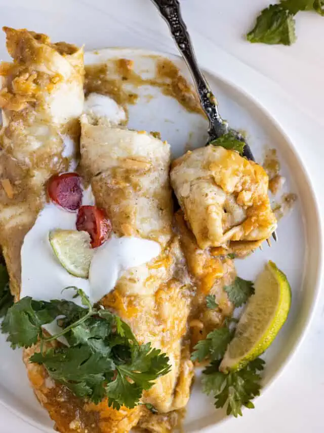 Overhead view of enchiladas on a plate with a fork taking a bite out.