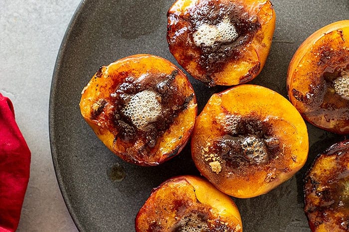 Grilled peaches with butter and spices on a plate.