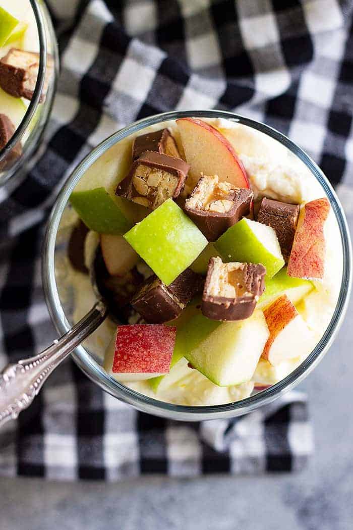 Top view of Snicker apple salad in a small glass bowl with a spoon.