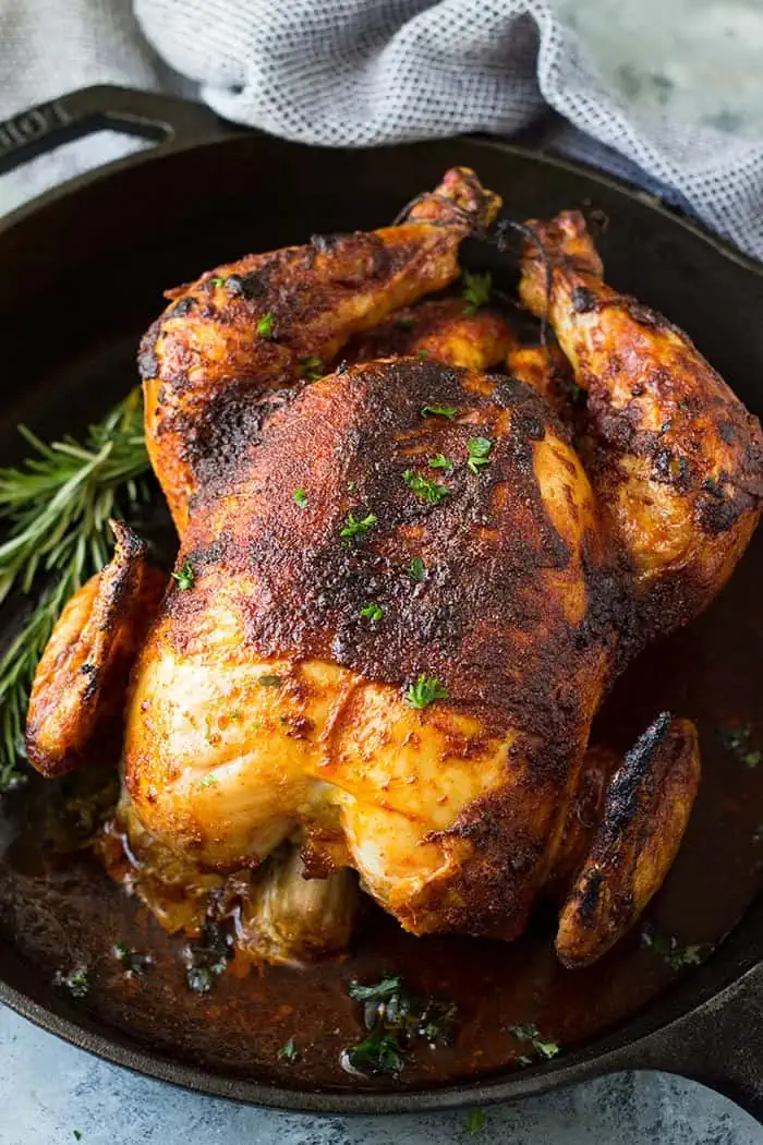 Baked rotisserie chicken in cast iron skillet with fresh herbs on top. 