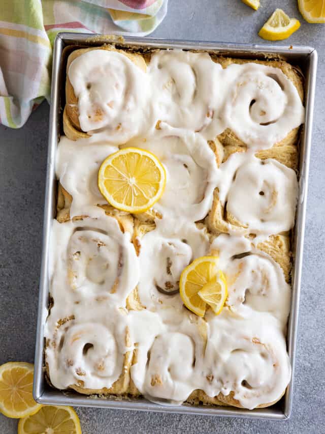 Overhead view of a pan of lemon sweet rolls topped with a cream cheese frosting and garnished with a few lemon slices.