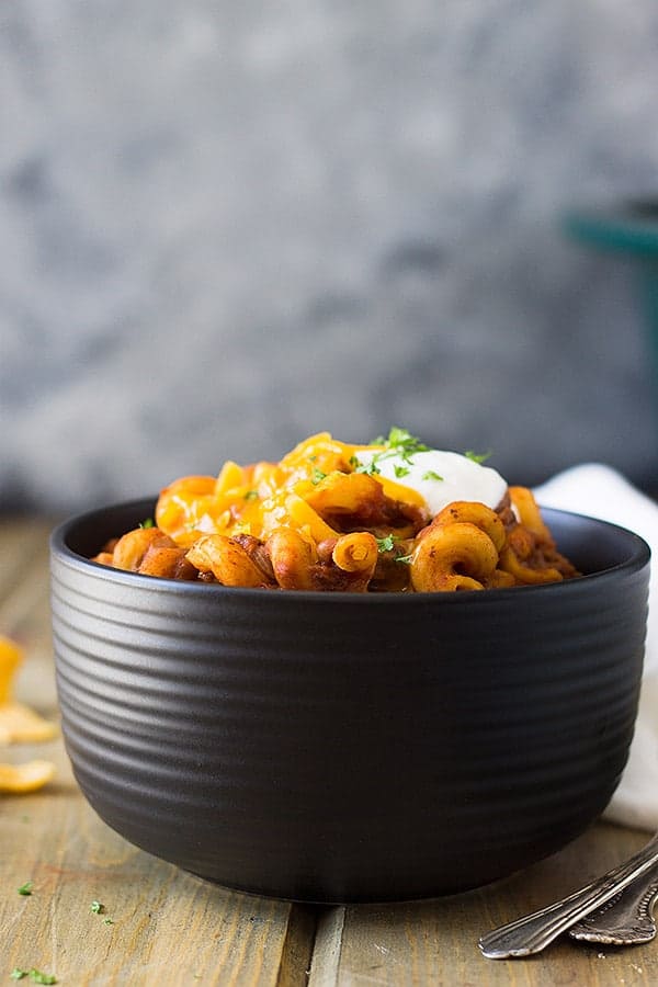 bowl of chili mac topped with sour cream and cheddar