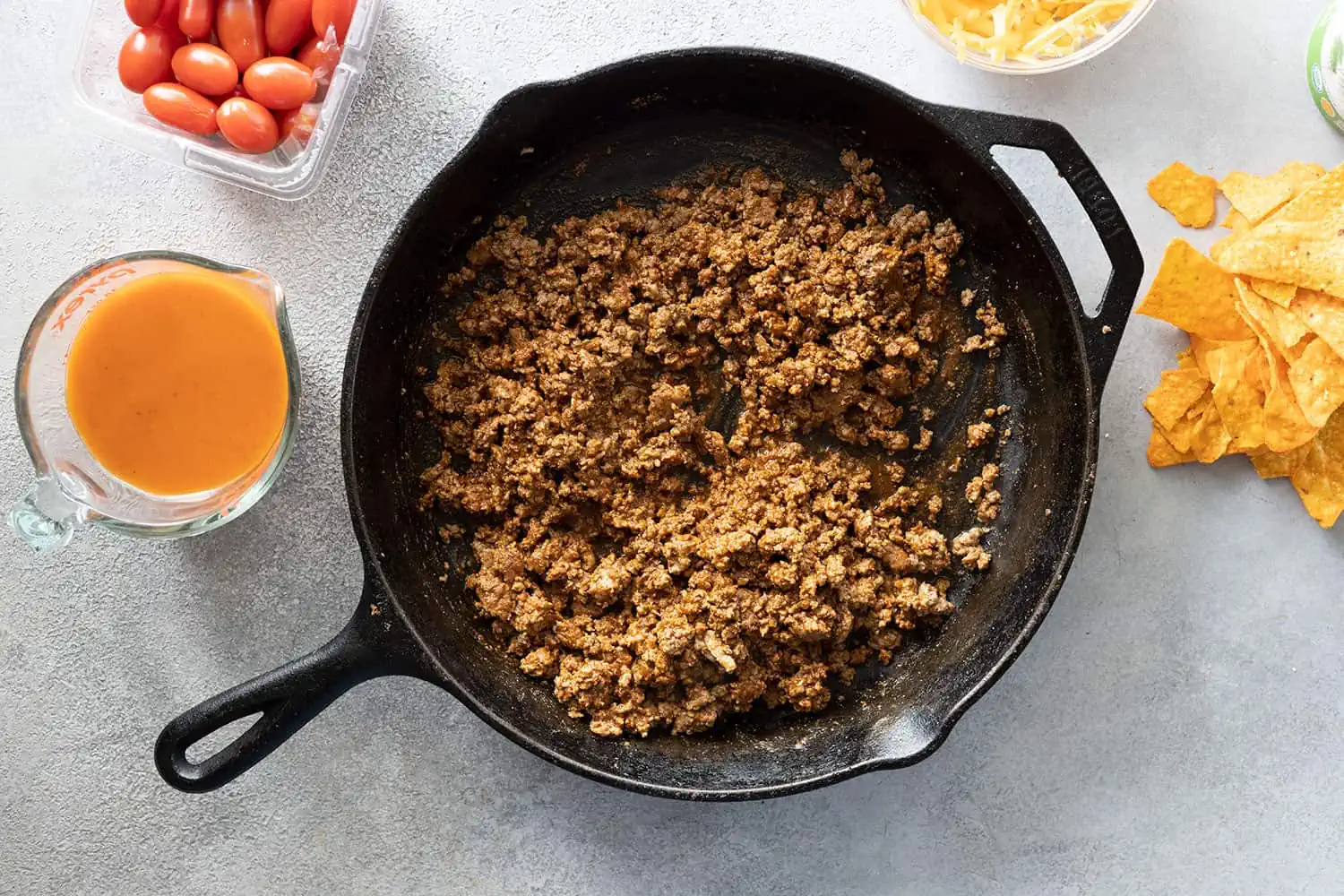 Overhead picture of taco meat in a cast iron skillet. Other ingredients off to the side.