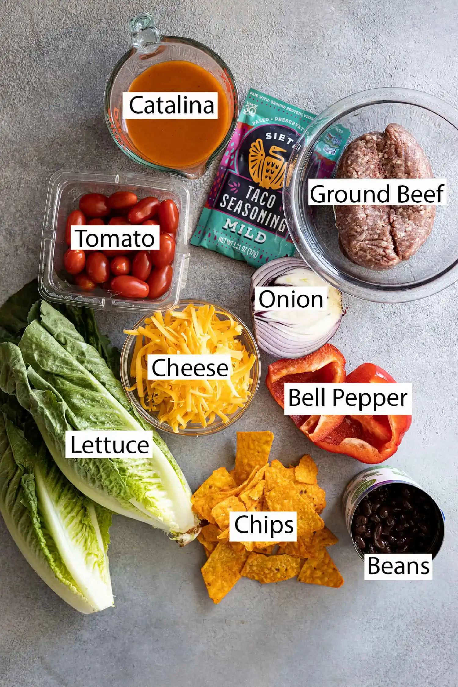 Ingredients: ground beef, taco seasoning, catalina dressing, tomato, onion, cheese, bell pepper, lettuce, beans, chips. 