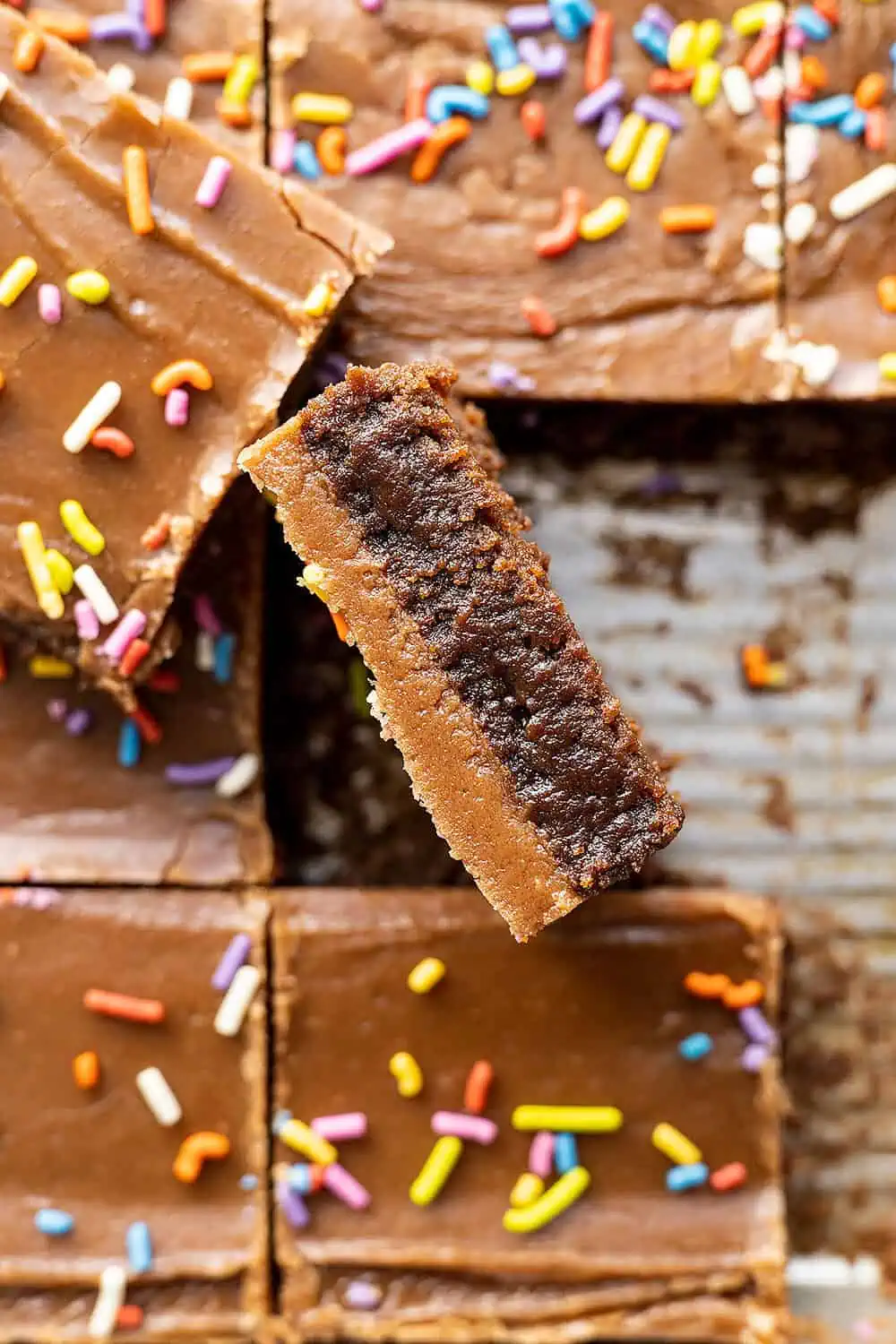 Overhead view of brownies cut with one turned on edge showing the brownie and the frosting. 