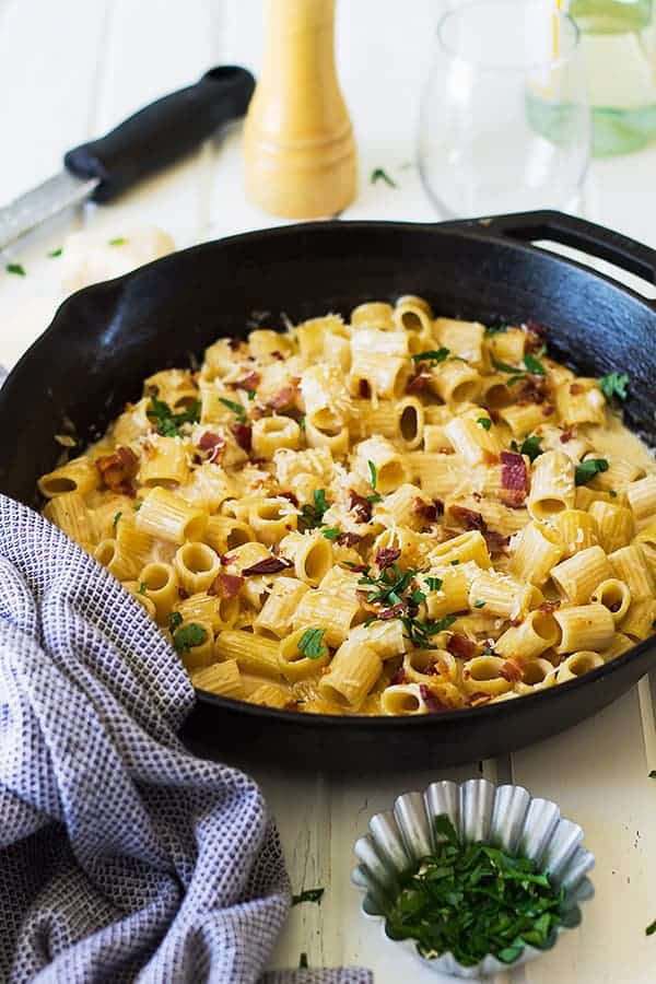 alfredo bacon pasta in a large skillet with fresh herbs