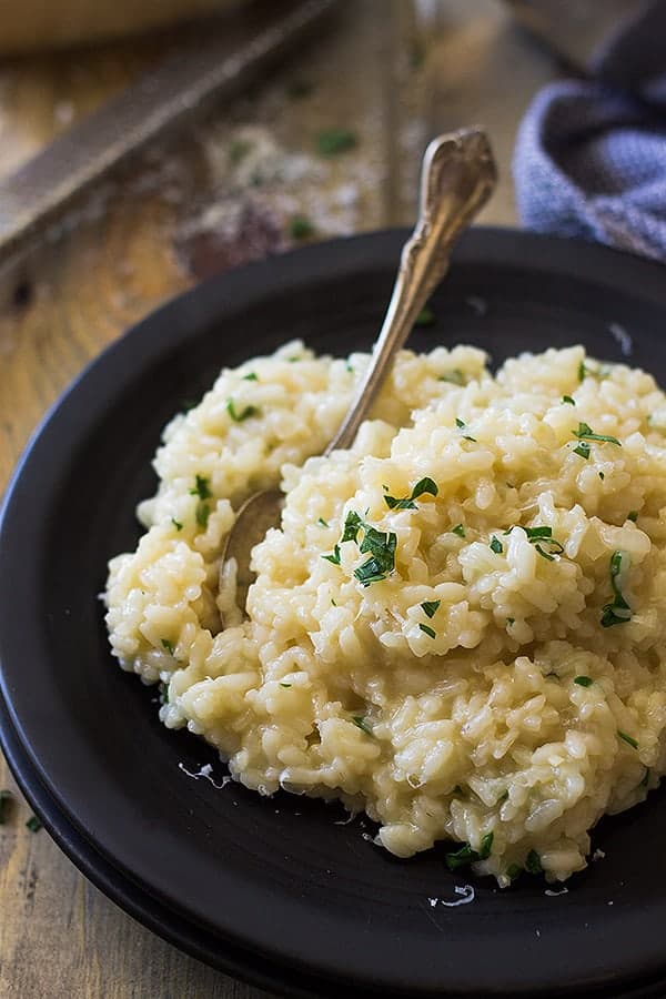 a black plate with easy risotto topped with fresh chopped parsley and a fork