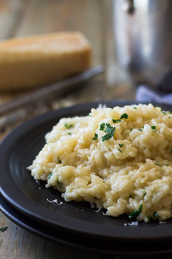 a black plate with easy parmesan risotto and fresh parsley on top