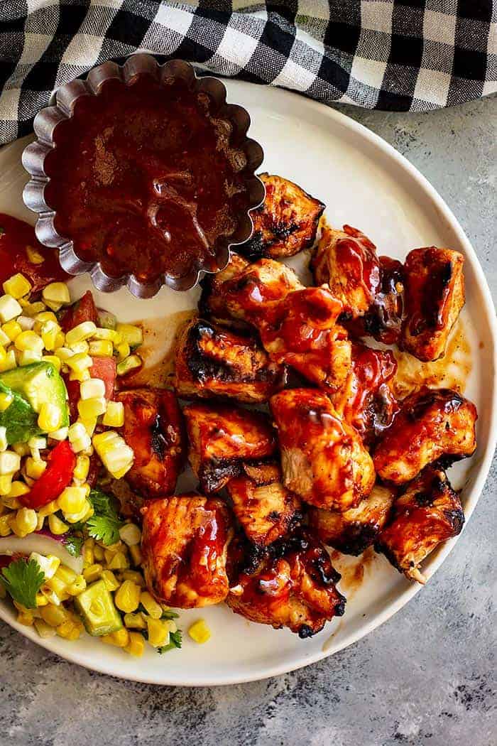 overhead: a plate with BBQ kabobs, homemade BBQ sauce, and a fresh veggie salad