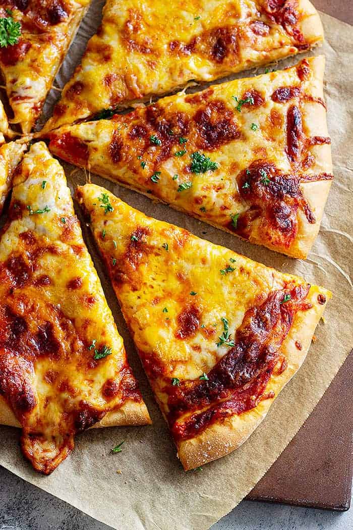 overhead: cooked and sliced cheese pizza on parchment paper