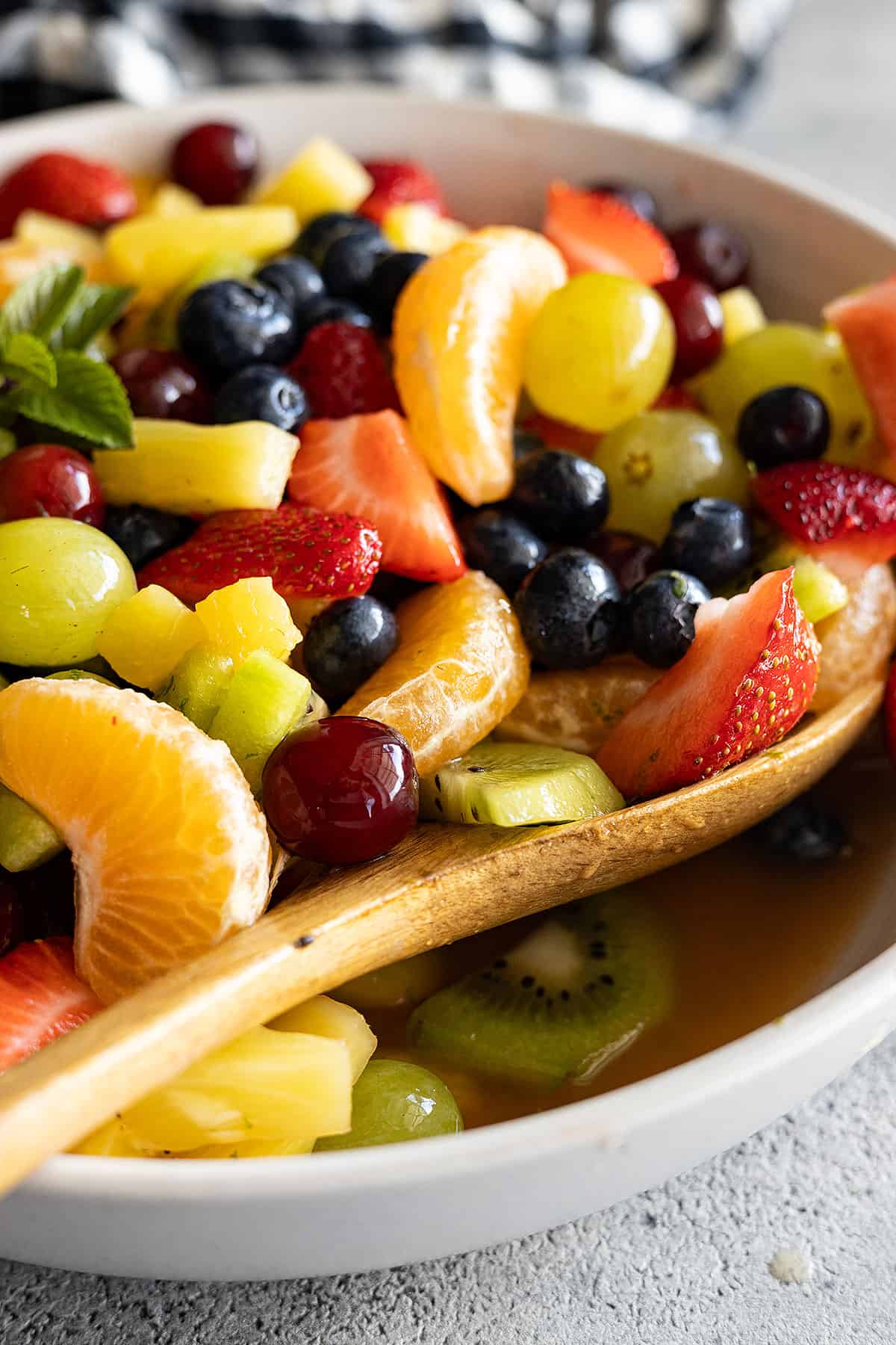 Fruit salad in a cream bowl with spoon off to the side ready to scoop up some fruit salad.