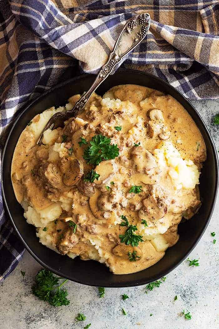 overhead: ground beef stroganoff over mashed potatoes in a black bowl