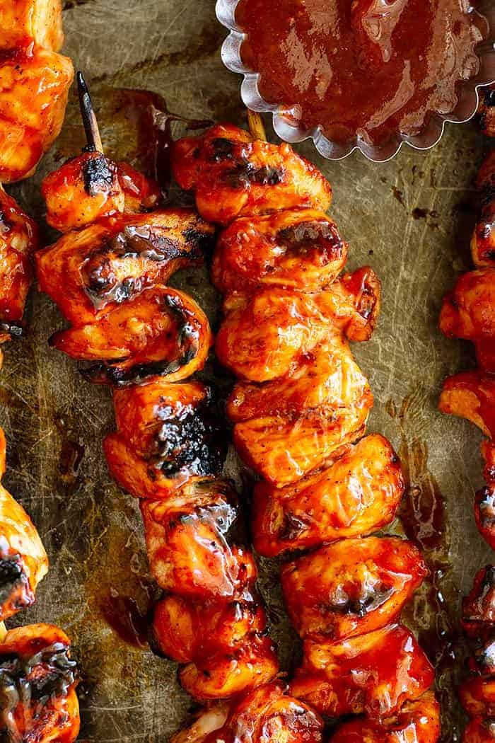 overhead closeup: kabobs with bbq chicken marinade on a baking sheet