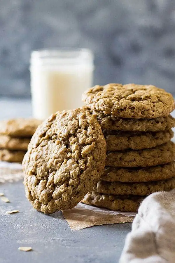 a stack of old fashioned oatmeal cookie recipe cookies with a glass of milk visible