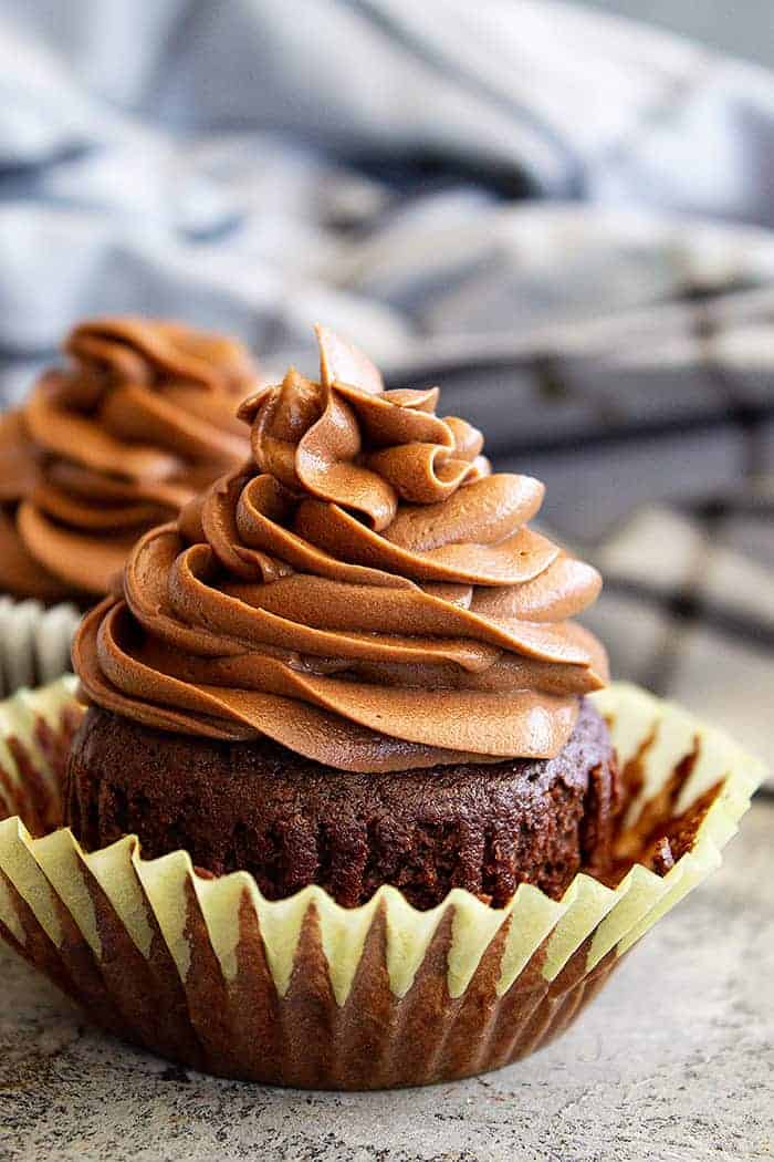 closeup: chocolate cream cheese frosting piped in a swirl on top of a chocolate cupcake