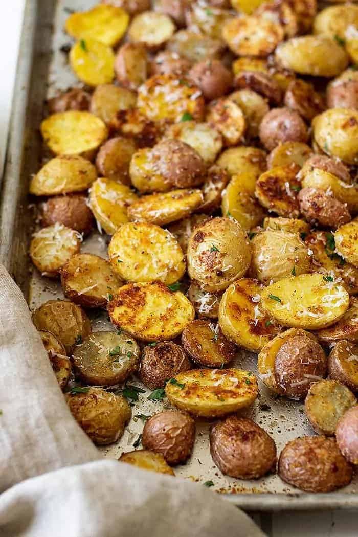 golden brown oven roasted Parmesan potatoes on a sheet pan fresh from the oven and topped with Parmesan cheese