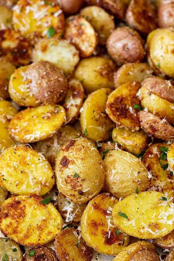 closeup: golden roasted Parmesan potatoes sprinkled with fresh Parmesan and parsley