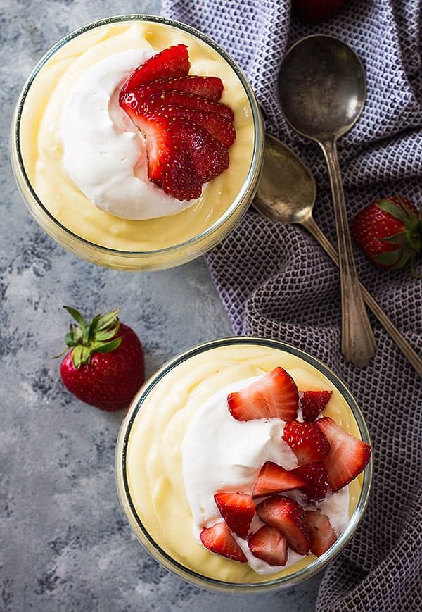 overhead: 2 small bowls of vanilla pudding with whipped cream and fresh strawberries on top