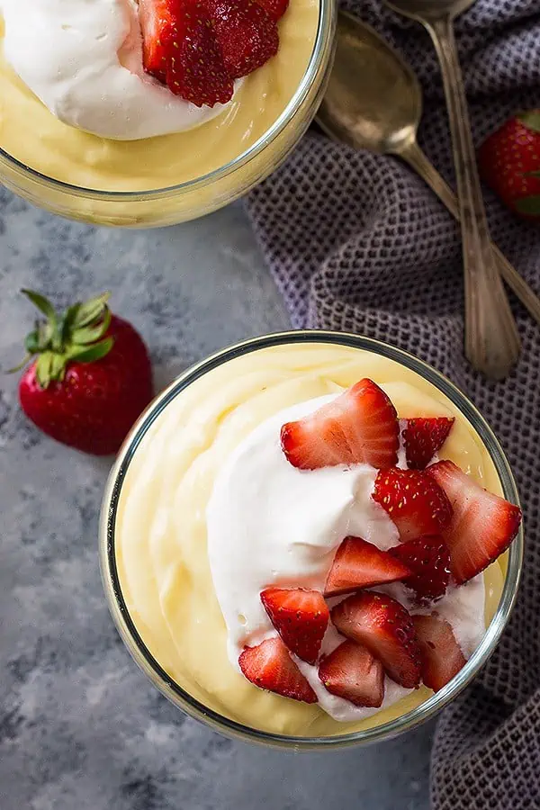 overhead: vanilla pudding recipe in a small bowl topped with whipped cream and fresh strawberries