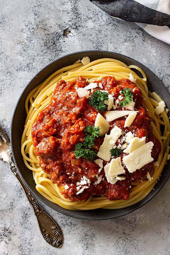 overhead: crock pot spaghetti sauce over noodles and topped with cheese
