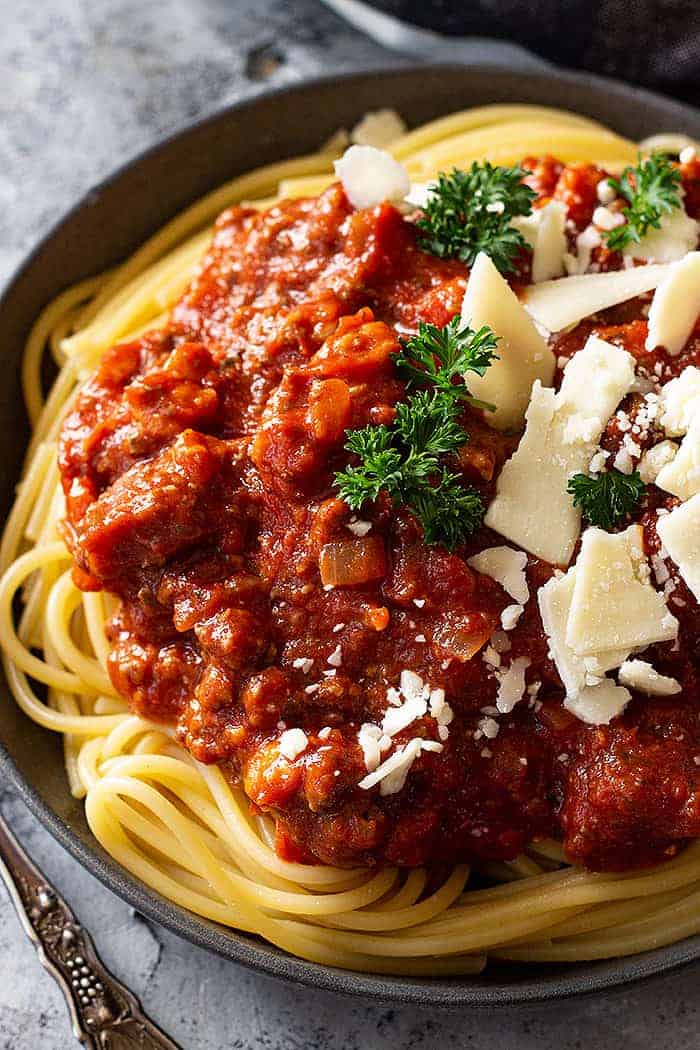 overhead closeup: a large plate of spaghetti piled high with crockpot spaghetti sauce recipe and cheese