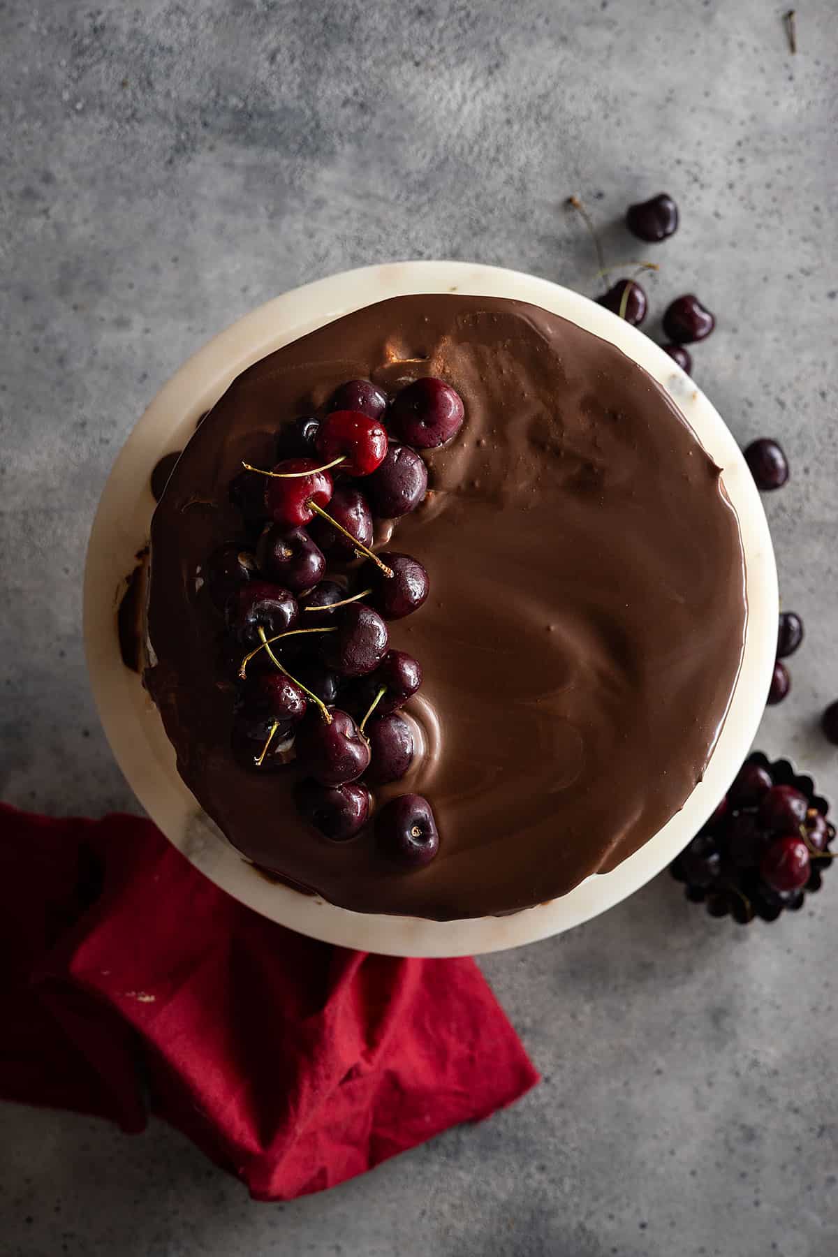 Overhead view of black forest cake topped with chocolate ganache and fresh cherries.