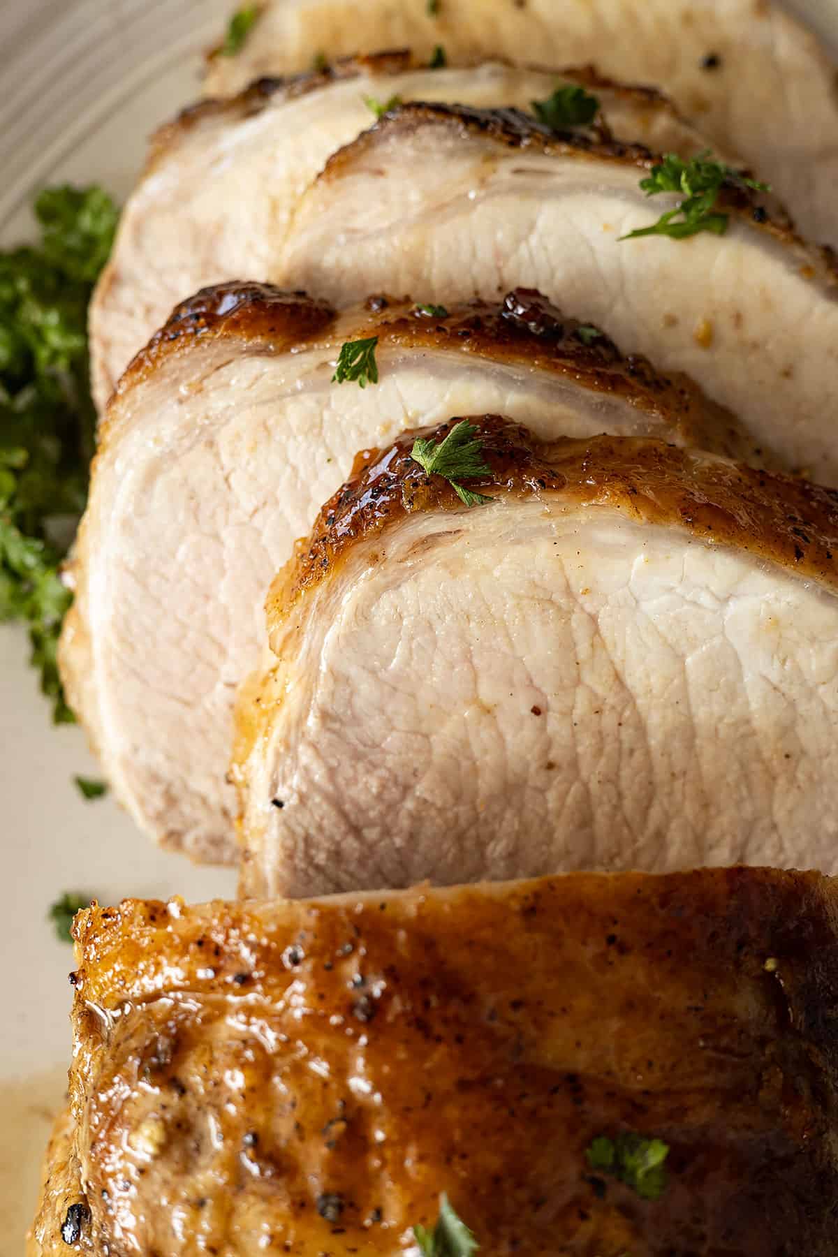 Close up of slices of pork loin. Garnished with parsley. 