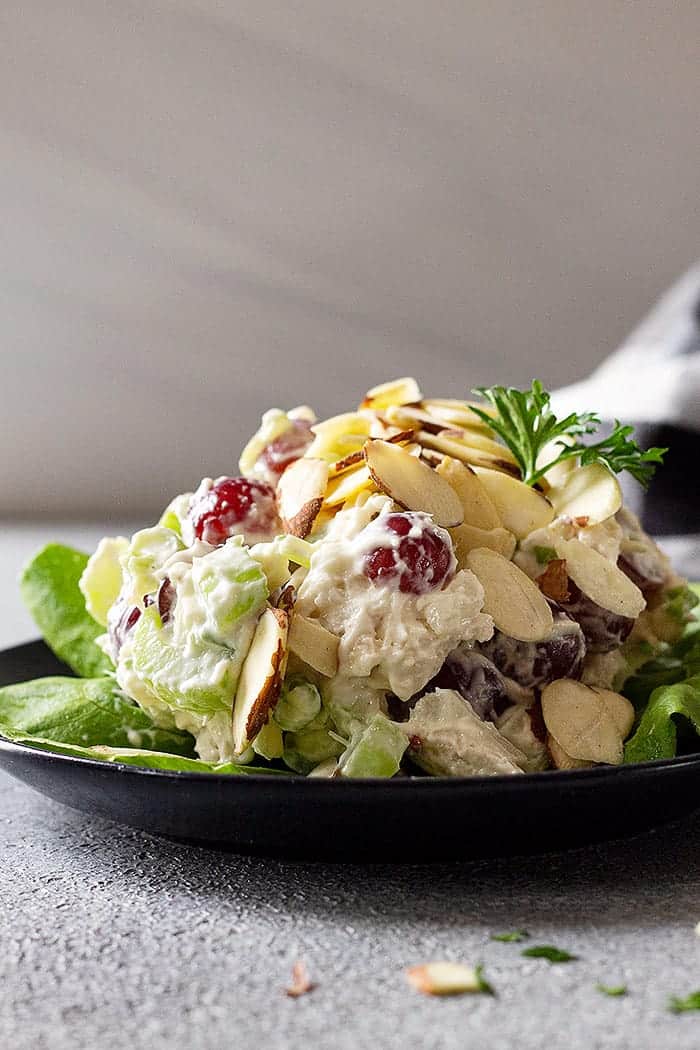 plate of creamy chicken salad on lettuce topped with sliced almonds