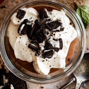 Overhead view of pudding in a small bowl topped with whipped cream and crushed oreos.