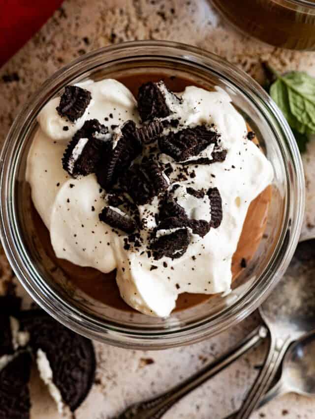 Overhead view of pudding in a small bowl topped with whipped cream and crushed oreos.