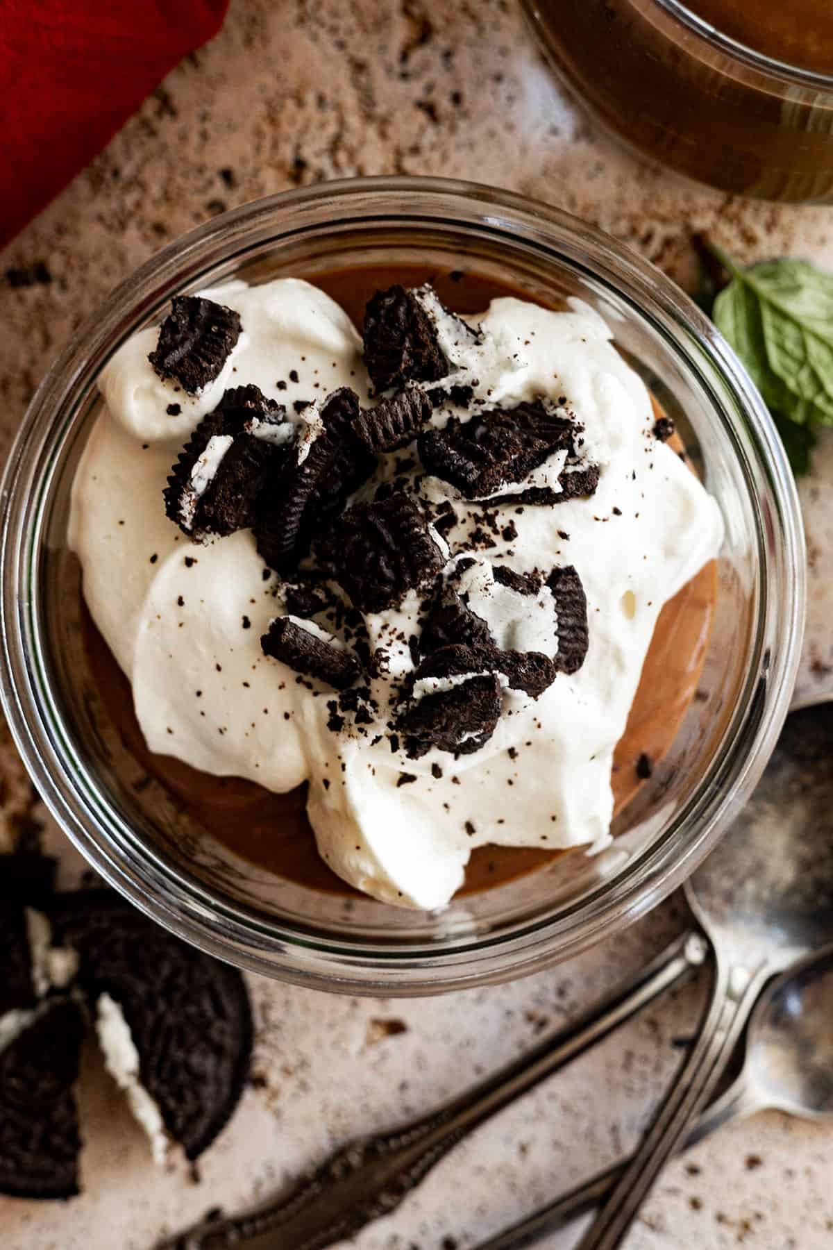 Overhead view of pudding in a small bowl topped with whipped cream and crushed oreos. 