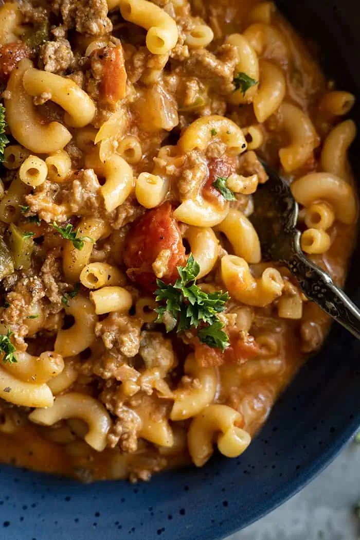 extreme closeup: recipe for American goulash with tomatoes and parsley showing
